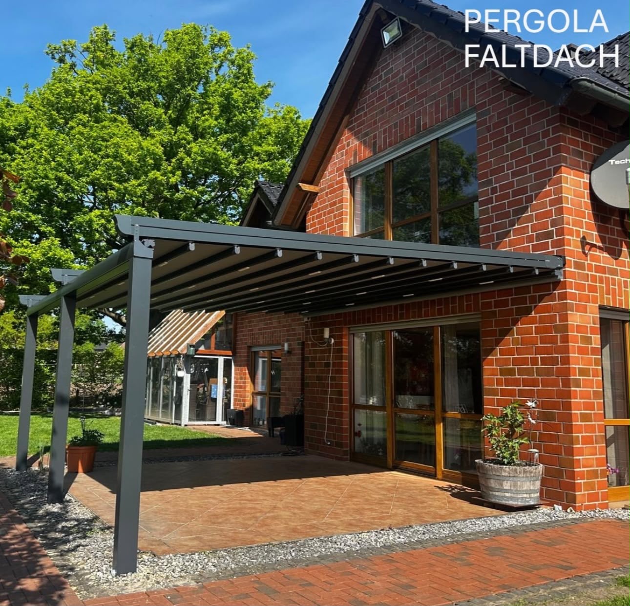 Pergola mit Faltdach an einem Klinkerhaus mit gepflasterter Terrasse
