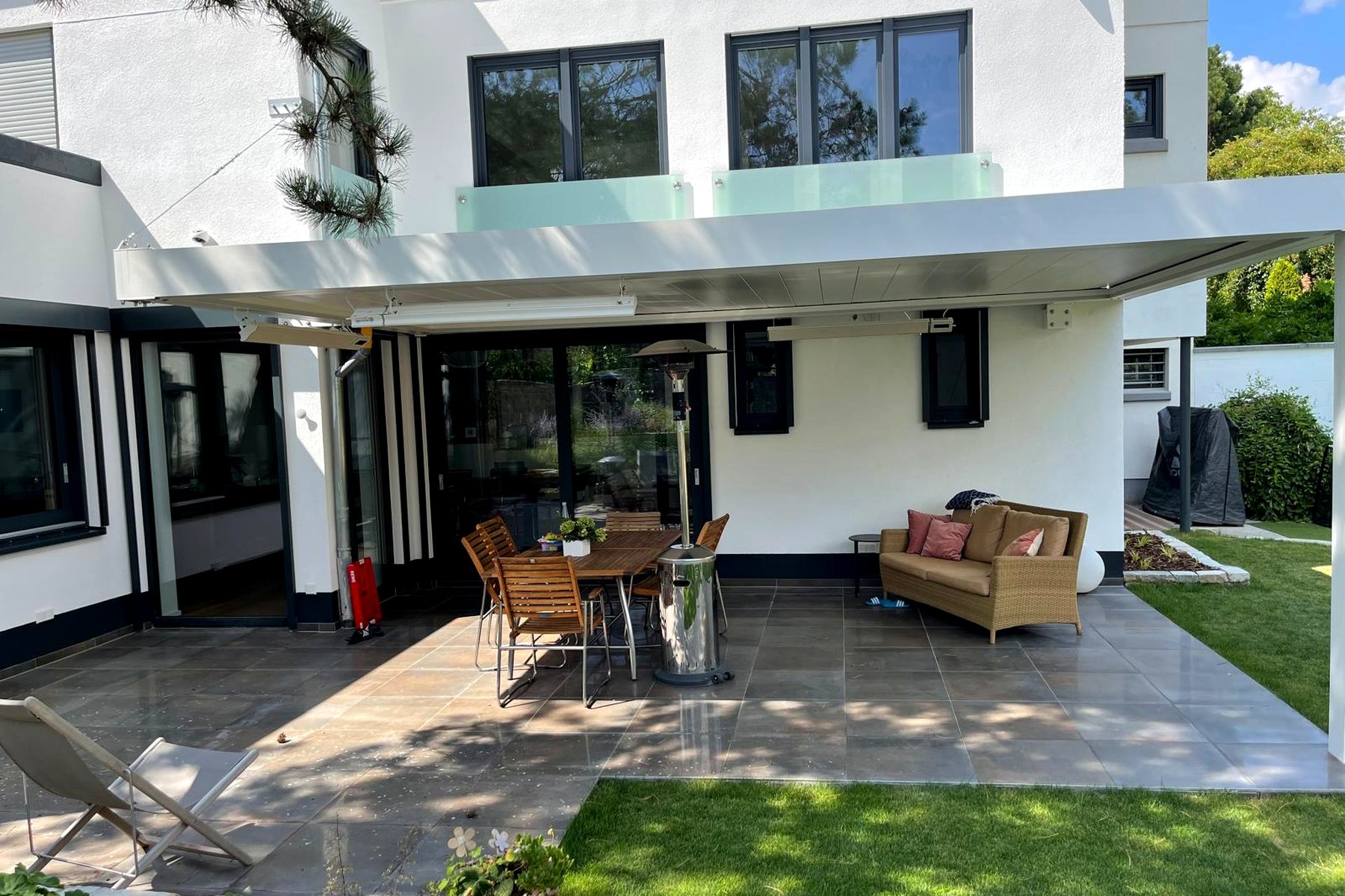 Lamellendach über einer möblierten Terrasse mit Sofas und Sesseln