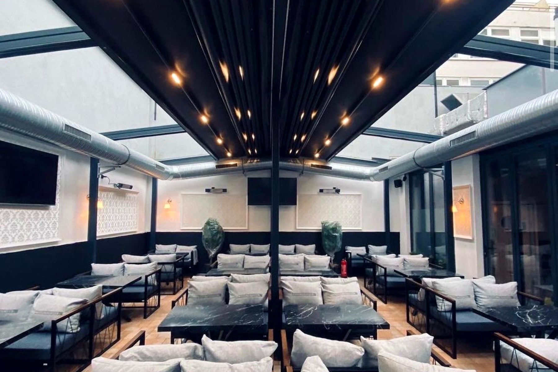 Verglaster Lounge-Bereich einer Gastronomie am Abend mit Spotbeleuchtung