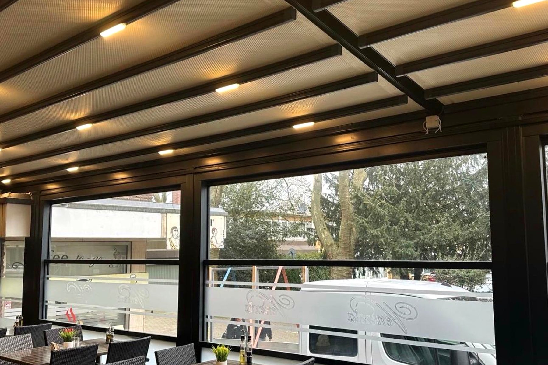 Gastronomie-Pergola von der Straße aus gesehen mit Beleuchtung im Dach