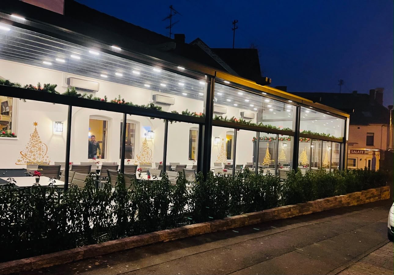 Beleuchtete Gastronomieüberdachung in der Abenddämmerung von der Straße aus gesehen