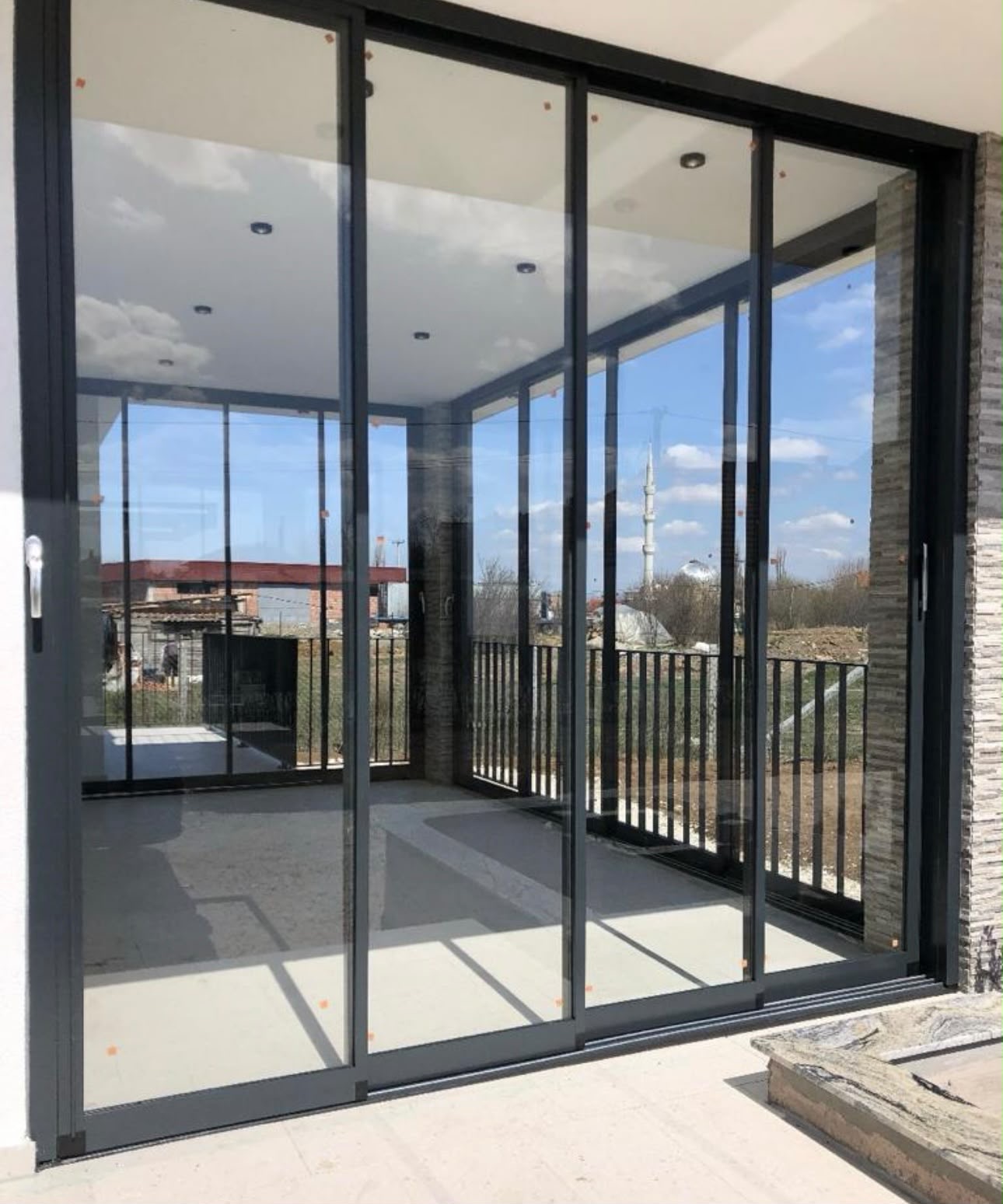 Glas-Schiebeanlage in anthrazitfarbenem Aluminiumrahmen auf einer Terrasse