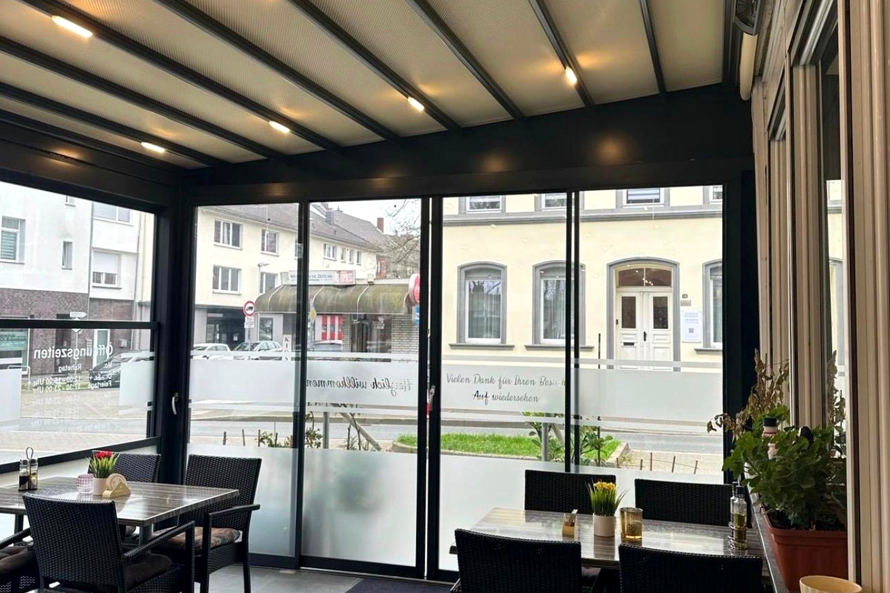 Gastronomie-Pergola von innen mit Tischen, Stühlen und Glasschiebeelementen